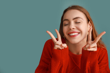 Pretty young woman showing peace gestures on blue background
