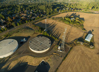 A large water tank is surrounded by a fence and a building