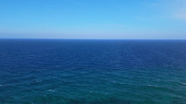 Gentle drone overview of clear open ocean with deep blue mysterious colors reaching to horizon