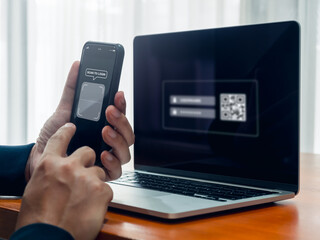 QR Code, multi factor authentication security concept. Digital scanner on smartphone camera lens frame with text, scan for login, holding by businessman hand while scanning on laptop computer screen.
