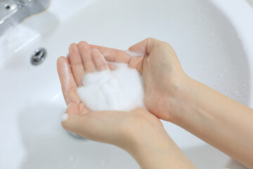 Washing hands in tap water with hand sanitizer foam in the sink, Korea