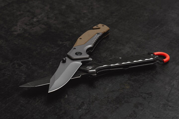 Two opened tactical military knives with sharp blade. Tool on dark concrete background.