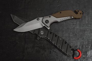 Two opened tactical military knives with sharp blade. Tool on dark concrete background.