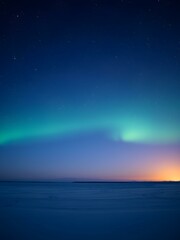 Fototapeta premium A cold, clear polar night sky with the faint glow of the sun on the horizon and a sky full of stars and aurora lights shimmering 