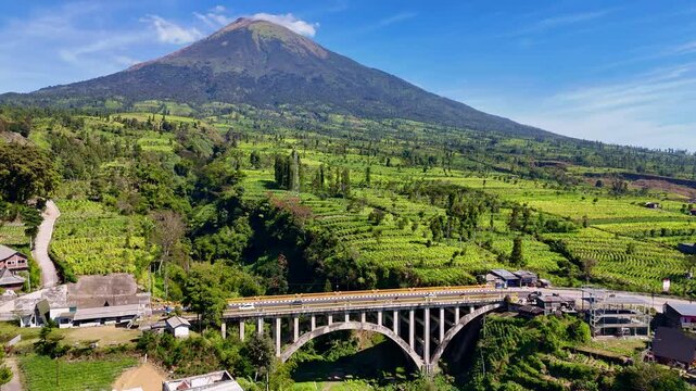 Beautiful scenery from bridge and mountain. Indonesian bridge with nature landscape of Mount Sindoro. 4K Aerial drone view of Sigandul Bridge.