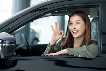 Woman Gesturing OK Sign Inside The Car At Showroom
