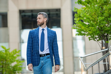 Businessman in business district wearing formal suit and walking outdoor expressing success, copy space