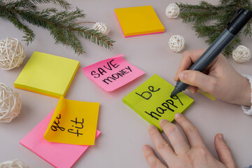 Female hands writing handwritten new year resolutions aims goals on sticky notes. Preparation for...