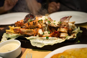 A picture of mixed seafood sizzler with prawns,fish,lobster,squid,vegetables and rice