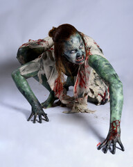 portrait of scary female model wearing spooky halloween costume, ripped clothes and fake blood like...