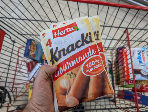 France, 12 August 2024 : Holding Knacki Sausages Package in Grocery Store Shopping Cart
