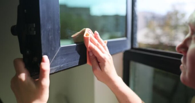 Cleaning window frames with rag on a sunny day
