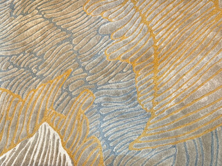 Random texture of custom bespoke carpet rug design, in fish skin, feather, floral, flower, and leaves foliage pattern. Beige and gold color. Luxurious seamless background carpet texture.