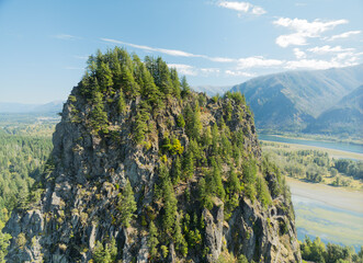 A mountain with a forest on top and a river below © Anton