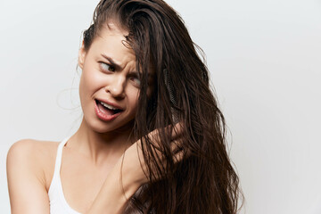 Naklejka premium Hair care, frustration with hair styling, woman with long wet hair, expressive facial expression, indoor white background showing personal grooming concept characters long
