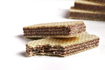 Pile of random wafers isolated on white background. Chocolate biscuit wafers filled with delicious chocolate cream. Dry and crispy wafers are ready to eat. bitten wafer
