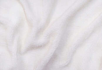 Fototapeta premium Top view of folded white soft sheepskin textile plaid. Artificial, fake fur. Warm cloth, bathrobe. Full frame
