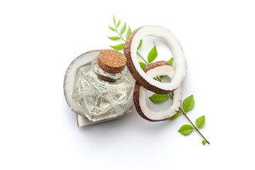 Top view of freshly cracked coconut fruit pieces, with coconut oil and Curry leaves. Isolated on a white background.