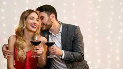 Affectionate man whispering love words to his girlfriend on date in restaurant, romantic couple having Valentine dinner together