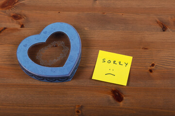 Heart-Shaped Box with Apology Note on Wooden Table - Expressing Regret and Seeking Forgiveness