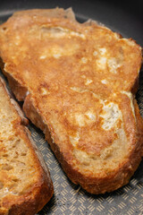 A piece of toast is brown and crispy, with a slightly burnt edge
