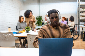 African man working using laptop and headphones in a coworking