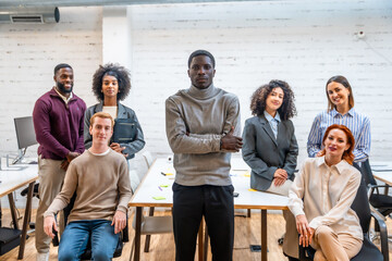 African man standing next colleagues sitting around a coworking table