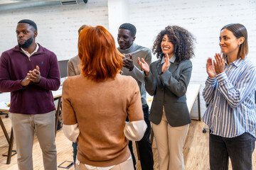 Colleagues applauding to a woman during project presentation in a coworking