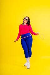 Pretty smiling plump female in sporty top and leggings holding jumping rope in hands