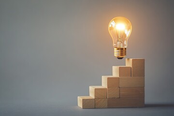 Light bulb on top of wooden blocks in the shape of stairs
