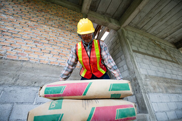 Worker is unloading the bags of cement an apartment is under construction, remodeling, renovation,...