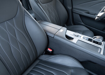 Obraz premium Modern luxury car black leather interior. Part of black leather car seat details with white stitching. Interior of prestige car. Comfortable perforated leather seats. Perforated leather..