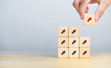 Businessman hand picked wooden block with red arrow. Individual and standing out from the crowd...