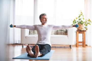 Handsome man exercising at home on gym mat. Routine home workout for a middle-aged man.