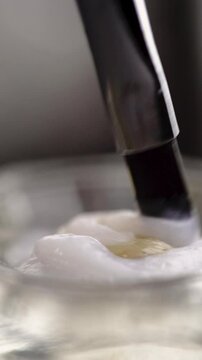Eyebrow coloring. Close-up of a beautician's hand mixing dye and oxidizer with a brush for coloring hair on the face