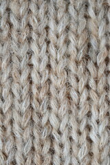 The texture of fabric thick beige sweater close-up. Knitted texture background