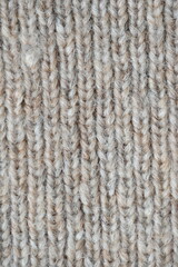 The texture of fabric thick beige sweater close-up. Knitted texture background