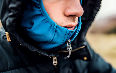 Close-up shot of the face of tourist bundled up in outdoor jacket with hood on.