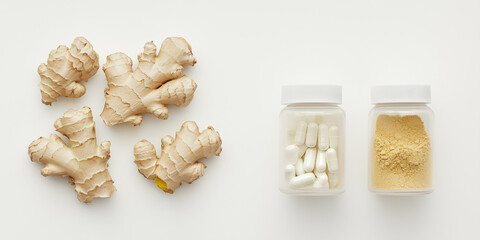 Fresh ginger root alongside bottles containing ginger capsules and ginger powder, symbolizing natural health supplements and herbal remedies.