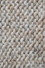 The texture of fabric thick beige sweater close-up. Knitted texture background
