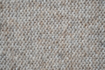 The texture of fabric thick beige sweater close-up. Knitted texture background