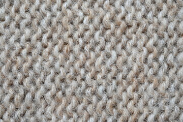 The texture of fabric thick beige sweater close-up. Knitted texture background