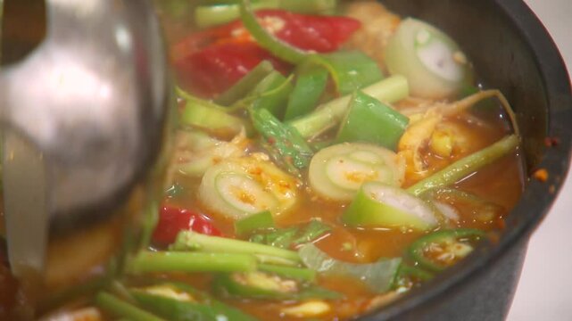 신선한 채소가 들어간 찌개를 국자와 숟가락으로 젓기