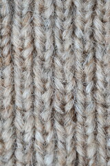The texture of fabric thick beige sweater close-up. Knitted texture background