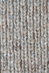 The texture of fabric thick beige sweater close-up. Knitted texture background