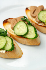 Savory canapes topped with creamy spread and cucumber slices served on toasted bread at a casual gathering