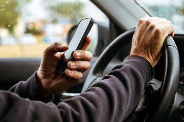 Male driver is driving car and texting on mobile phone