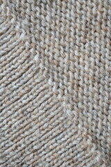 The texture of fabric thick beige sweater close-up. Knitted texture background