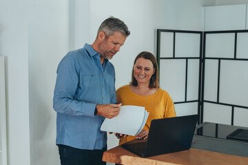 Obraz premium Man and woman smiling professional business people talking using laptop computer working in office.