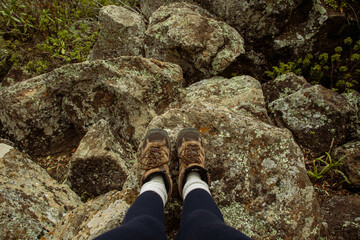 A hiker standing on a rock on the peak of a mountain